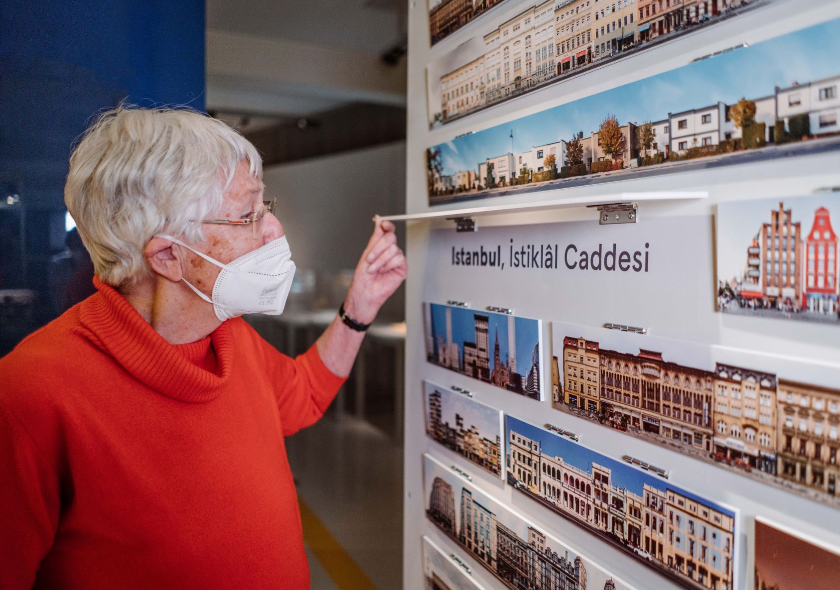 Eine &auml;ltere Dame klappt ein Stadtansicht nach oben und liest, um welche Stadt es sich handelt.