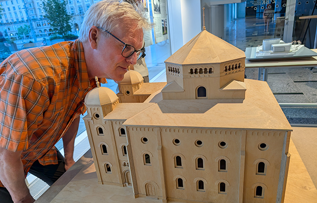 Ein &auml;lterer Herr beugt sich &uuml;ber das h&ouml;lzerne Architekturmodell einer Synagoge.
