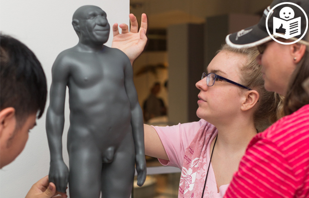 Das Bild zeigt drei Menschen an dem Modell eines Neandertalers