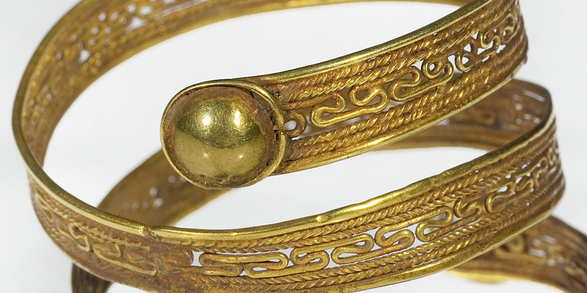 Goldener spiralf&ouml;rmiger Armreif mit feinem geschwungenen Muster.