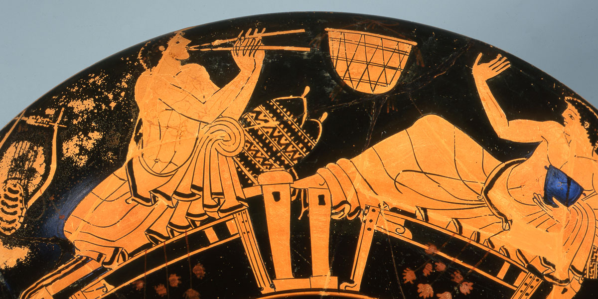 Ausschnitt eines Fotos einer griechischen Schale. Auf schwarzem Hintergrund ist in heller Farbe ein Gelage zu sehen. Zwei Männer sitzen auf Stühlen und spielen Instrumente.