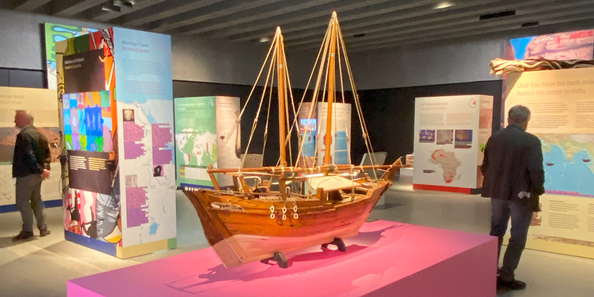 In einem Ausstellungsraum steht auf einem pinken Sockel das Modell eines großen Segelschiffes aus dem 18. Jahrhundert.