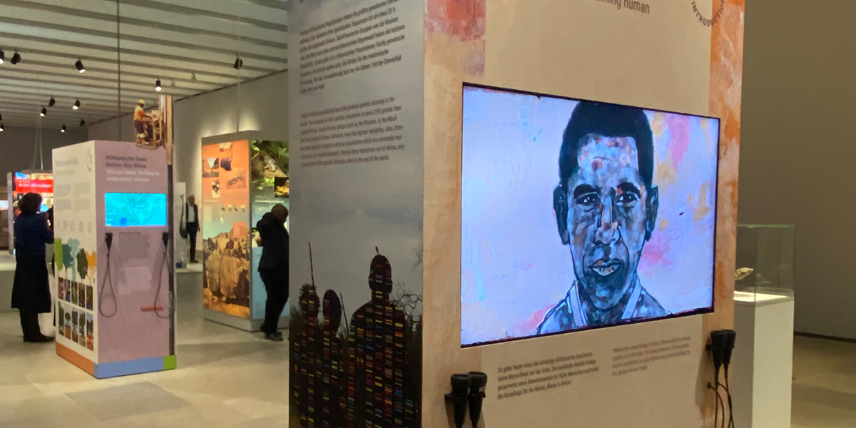 In einem Ausstellungsraum stehen 3 große Textsäulen. Auf dem vorderen ist ein verfremdetes Gemälde des ehemaligen US-Präsidenten Barack Obama zu sehen.