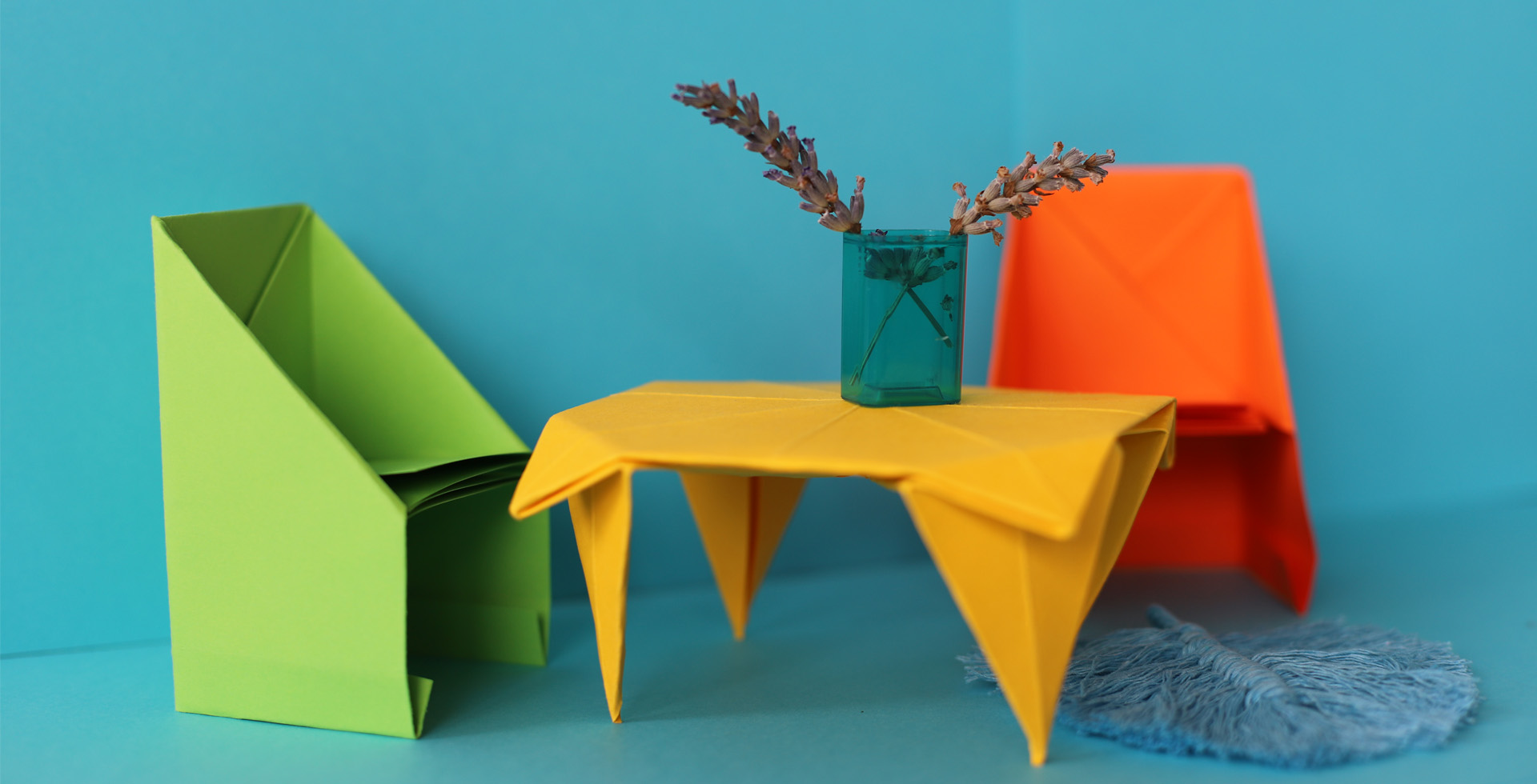 Das Foto zeigt einen Tisch und 2 Stühle, die aus Papier in Origamitechnik gefaltet sind.