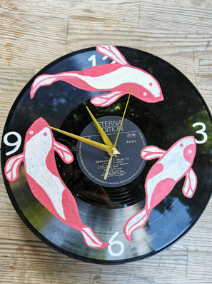 Das Foto zeigt eine 33er-Schallplatte, die mit Fischen bemalt ist und Uhrzeiger hat.