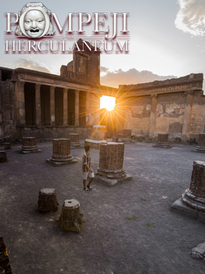 Das Foto zeigt römische Ruinen in der antiken Stadt Pompeji beim Sonnenuntergang. Durch einen Torbogen blendet die untergehende Sonne.