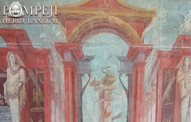 Foto einer bunten römischen Wandmalerei mit einem gemalten Torbogen, das von zwei Statuen flankiert wird.