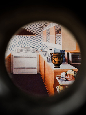 Das Foto zeigt einen Türspion, durch den man eine Küche erkennen kann. Ein griechisches Gefäß steht auf einer Küchenablage.