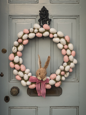 Foto eines Osterkranzes aus Wachteleiern und mit einem Stoffhasen. Der Kranz hängt an einer Tür.