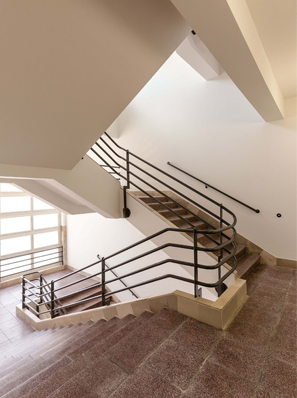Treppenhaus aus den 1930er Jahren mit einem elegant geschwungenen Geländer, das aus 4 parallelen Stangen besteht.