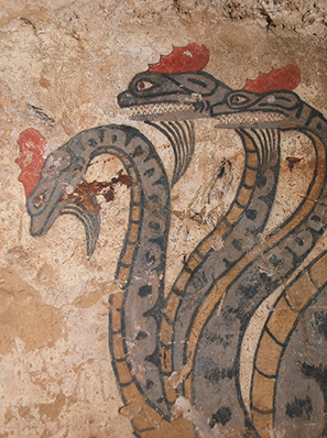 Auf einer Wand mit abgeblättertem Putz ist ein dreiköpfiger Drache gemalt.