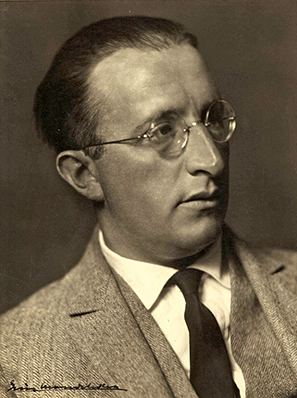 Altes Schwarz-Weiß-Foto eines Mannes mittleren Alters mit Nickebrille und zurückgekämmten Haaren.