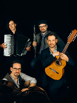 Vier Musiker vor schwarzem Hintergrund. Eine Frau mit Akkordeon sowie drei Männer mit Klarinette, Gitarre und Kontrabass.